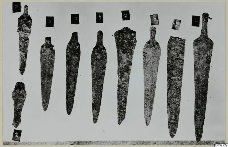 Bronze blades and tools from Lapithos Tomb 322A, laid out in a row with number labels