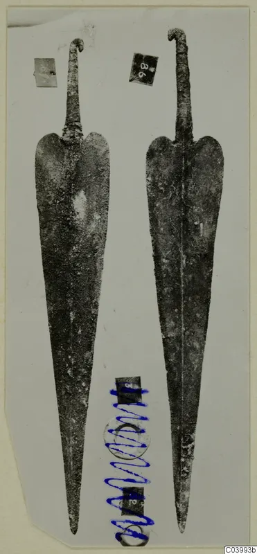 Two long metal weapon blades with curled tangs, from the Lapithos finds