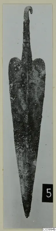 Corroded metal blade with a hooked tang, find from the Vrysi tou Barba tombs at Lapithos