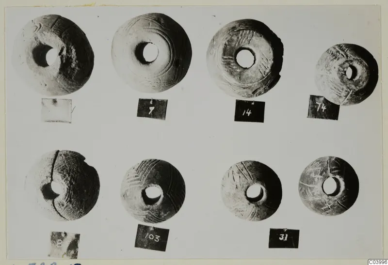 Eight disc-shaped objects with central holes and incised patterns, in two rows, small finds from L.322E.