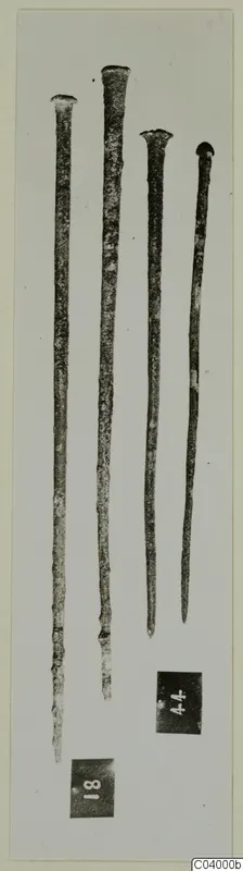 Four long slender bronze rods with flattened heads, photographed on a pale card with two number labels
