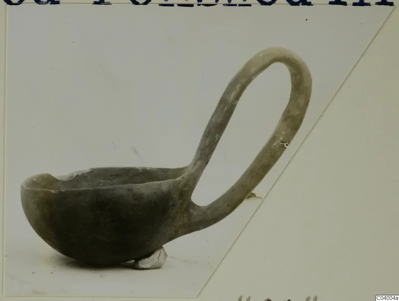 Deep bowl with a tall loop handle, photographed in side view on a pale background
