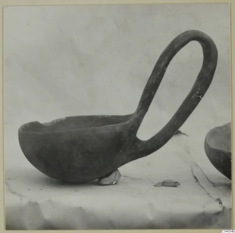 Red Polished III bowl with a tall loop handle, photographed in side view on a draped cloth.