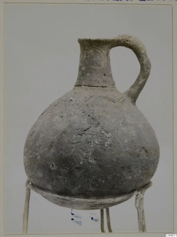 Red Polished III jug from Lapithos, Vrysi tou Barba tombs, shown on a wire stand