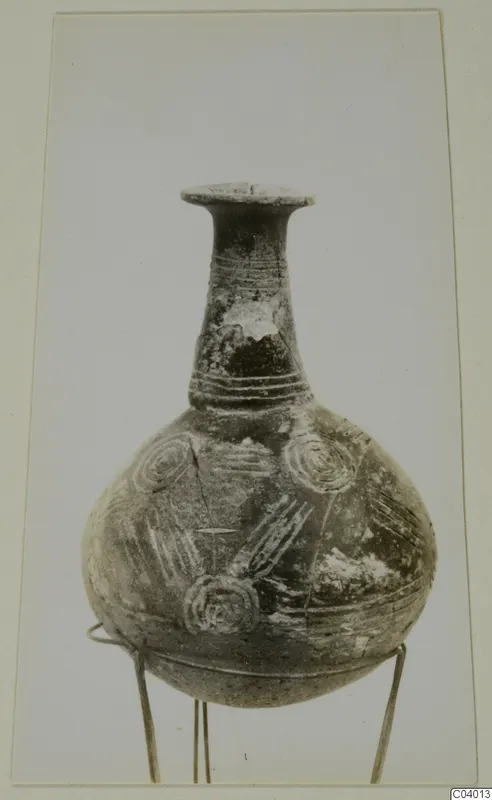 Pottery Black Polished vessel with a long neck, flared rim and incised circle decoration, standing on a wire stand