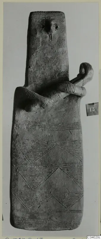 Terracotta idol, tall and flat, with incised bands and a small limbed figure clinging to its upper body