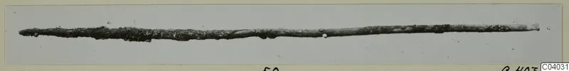 Corroded metal rod from Idalion, lying horizontally across a pale grey background