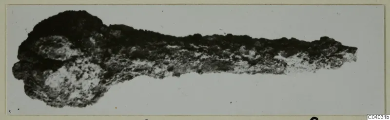 Corroded metal object from Idalion, Tomb 3, lying horizontally against a pale background
