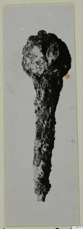 Corroded bronze object with a rounded head and long tapering shaft, from Idalion