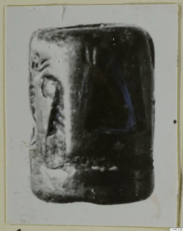 Stone seal with an engraved design on one side, photographed on a light card mount
