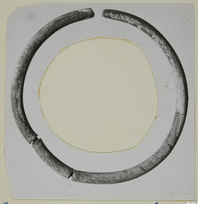 Open ring of silver with a round section, photographed on a grey card with a circular cut-out.