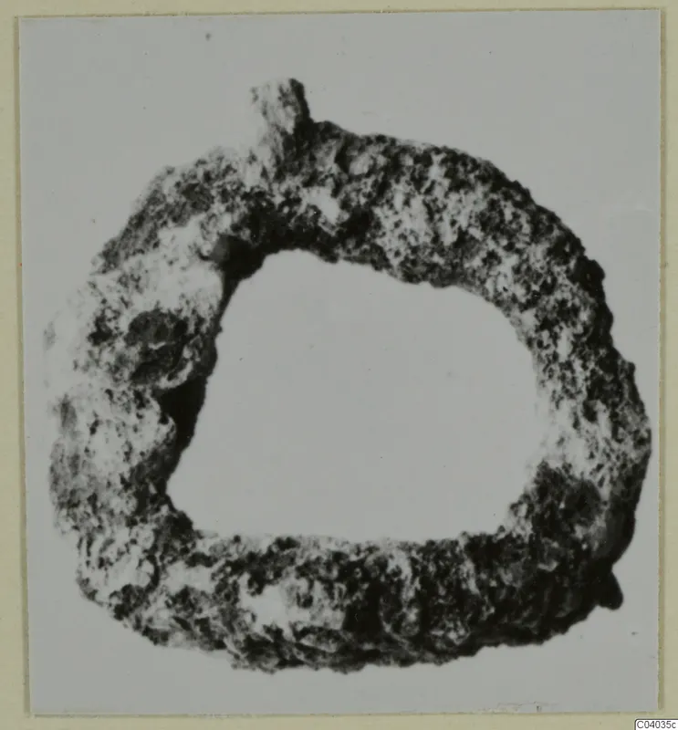 Corroded metal ring with a small knob on its upper edge, shown face on against a plain pale background.
