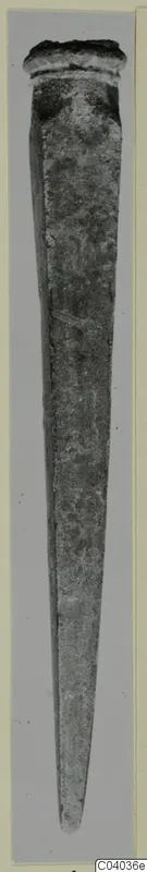Long tapering bronze object with a raised rim at its upper end, shown upright against a grey mount