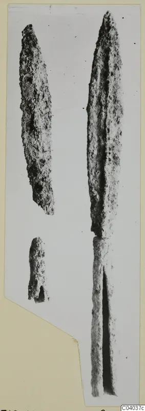 Iron weapon pieces: a long leaf-shaped blade and two smaller fragments, photographed on a card mount.