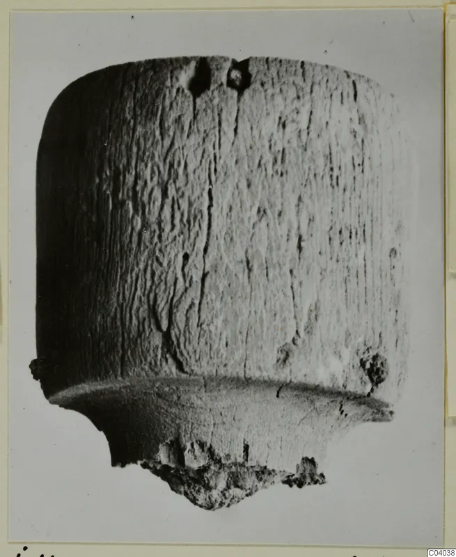 Cylindrical bone object with a wide flange near the base and a broken, crumbly lower end