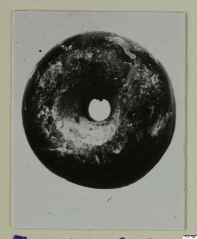 Dark disc-shaped piece of jewellery with a central hole, from Idalion