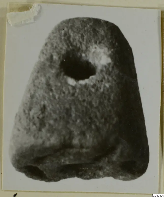Stone object with a rounded top and a large hole near the upper part, photographed on a card mount