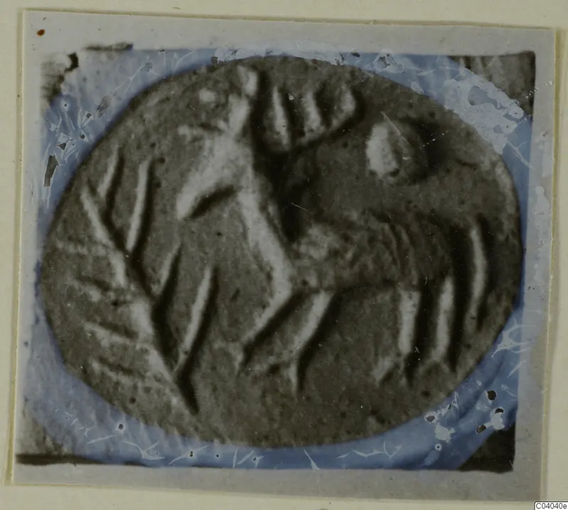 Oval engraved stone gem with carved lines, photographed on a light card mount with a blue-tinted border