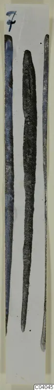 Three long, narrow bronze tools laid side by side on a white card.