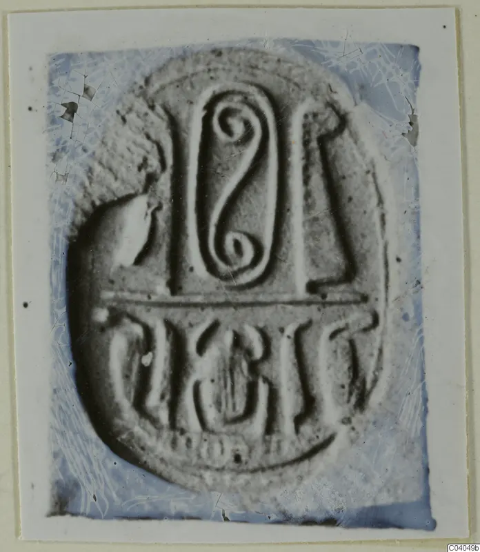 Oval seal or gem face with a spiral motif at the top, a horizontal bar and a row of incised signs below