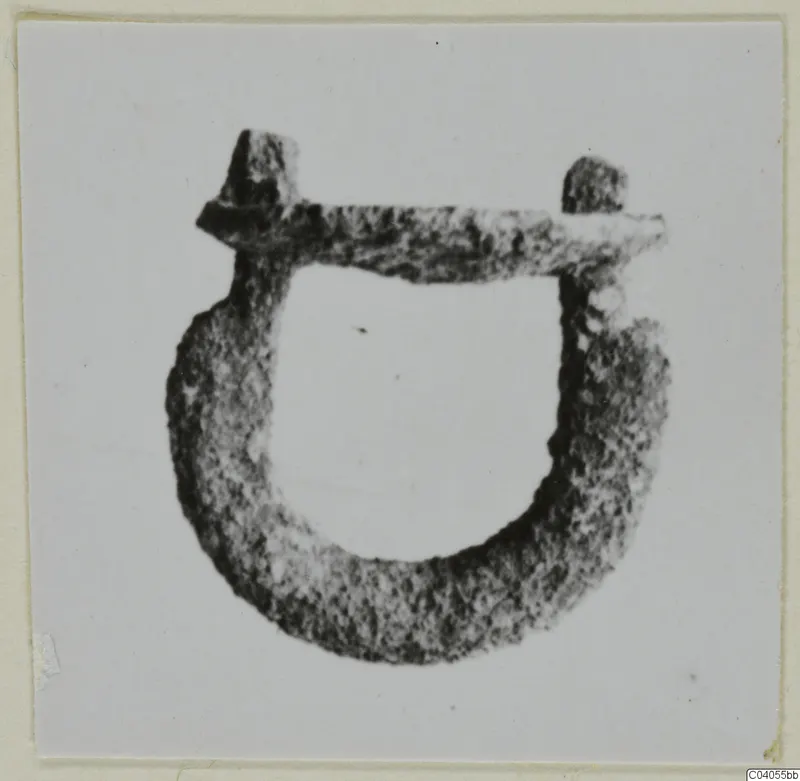 Corroded metal loop mounting with a bar across the top and a stub at each end, shown on a light card.