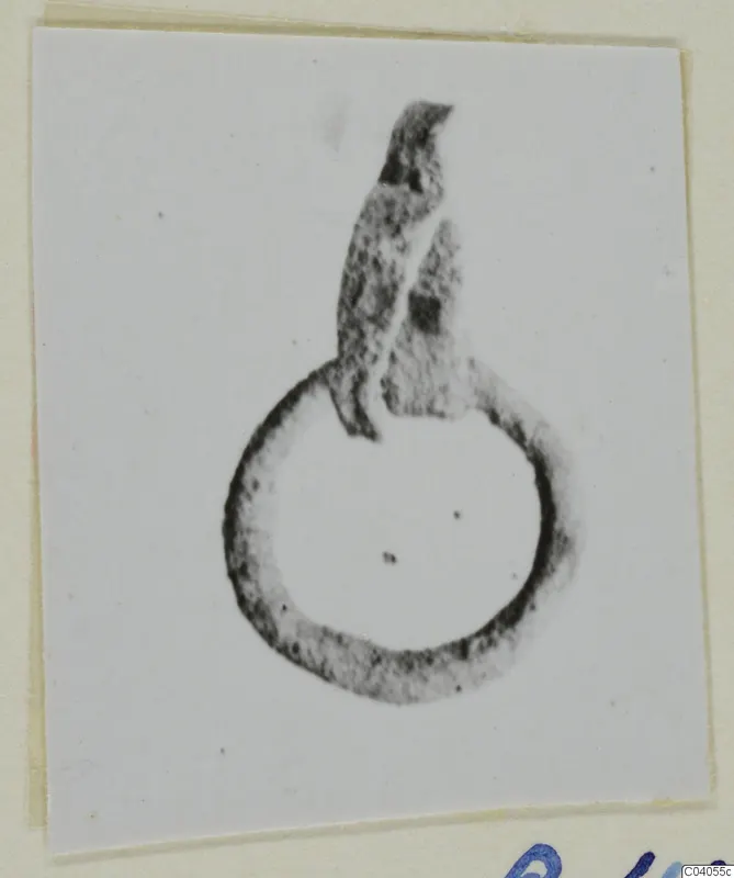 Bronze loop with a flattened, broken projection rising from its upper edge, photographed on a card mount