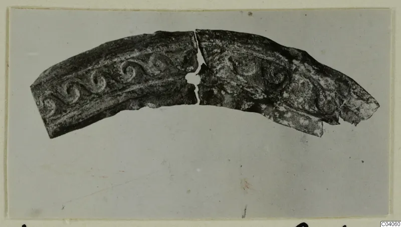 Curved metal fragment in two joined pieces, with raised spiral scroll decoration along its band, from Idalion