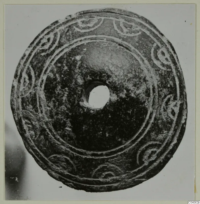 Disc-shaped piece of jewellery with a central hole and curled pattern in relief, from Idalion