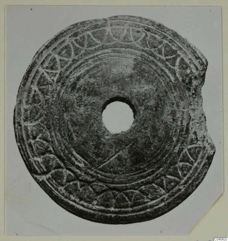 Flat disc with a central hole, incised concentric lines and an arc pattern around the edge, small find from Idalion