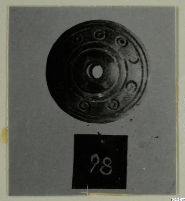 Disc-shaped object with a central hole and concentric rings, from Enkomi Tomb 6, shown with a number label.