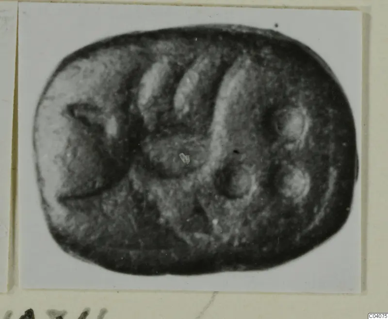 Engraved dark stone seal with a rounded, almost rectangular outline, shown in a photograph