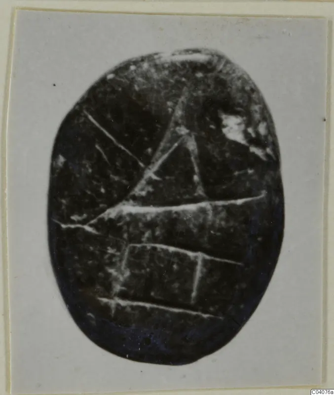 Oval dark stone seal or gem with incised linear design, shown on a mounted card