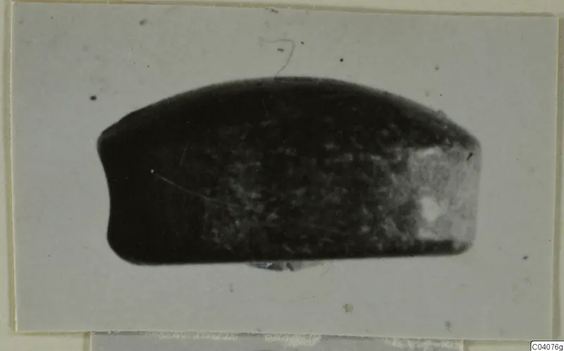 Glyptic A.I.2296, a small dark oval seal or gem photographed on a pale card