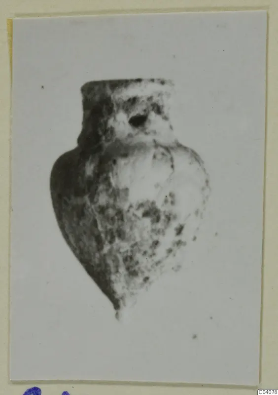 Small pendant-like object with a hole near its top, from Ayia Irini, shown on a mounted photograph.