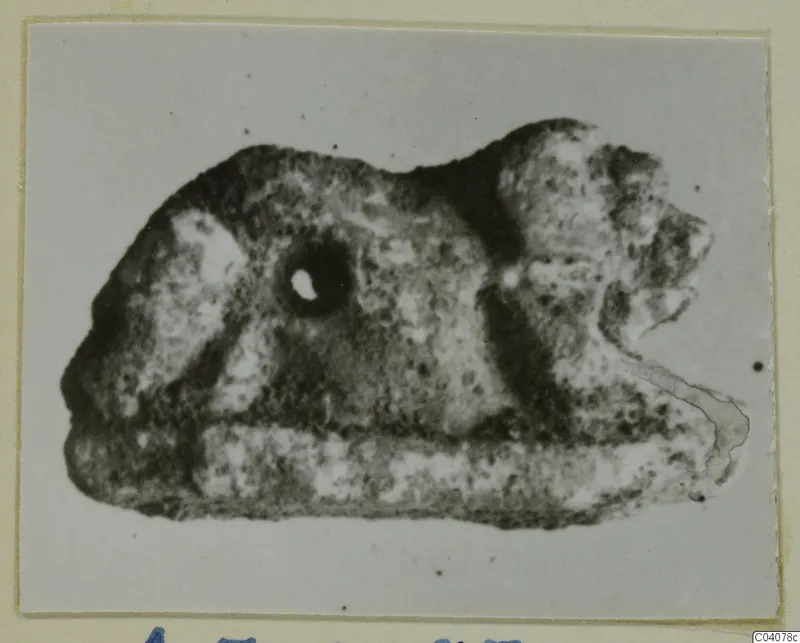 Small figure of a lion in side view, with a round hole pierced through its body near the head.