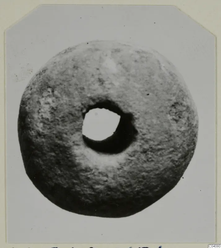 Ring-shaped stone find from Ayia Irini with a large central hole, photographed on a card mount
