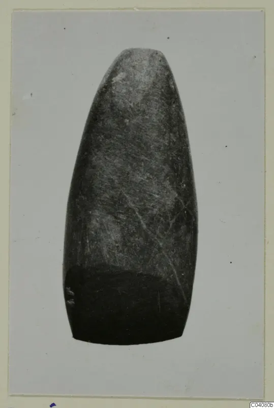 Elongated polished stone object, tapering to a rounded top, with a number label on its lower edge.