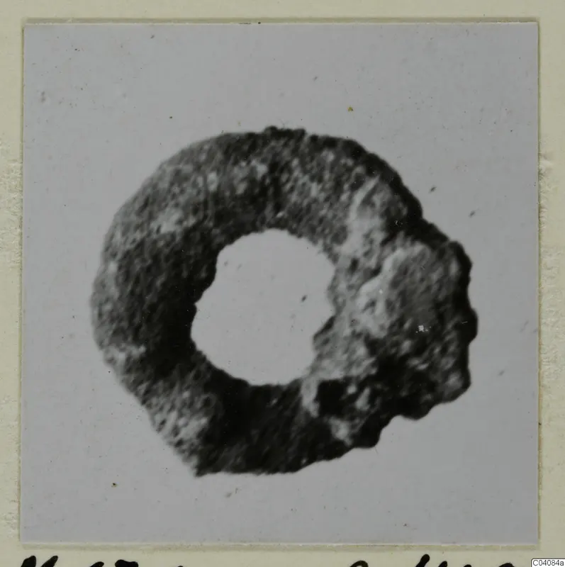 Corroded silver ring-shaped object with a round central hole, from Marion