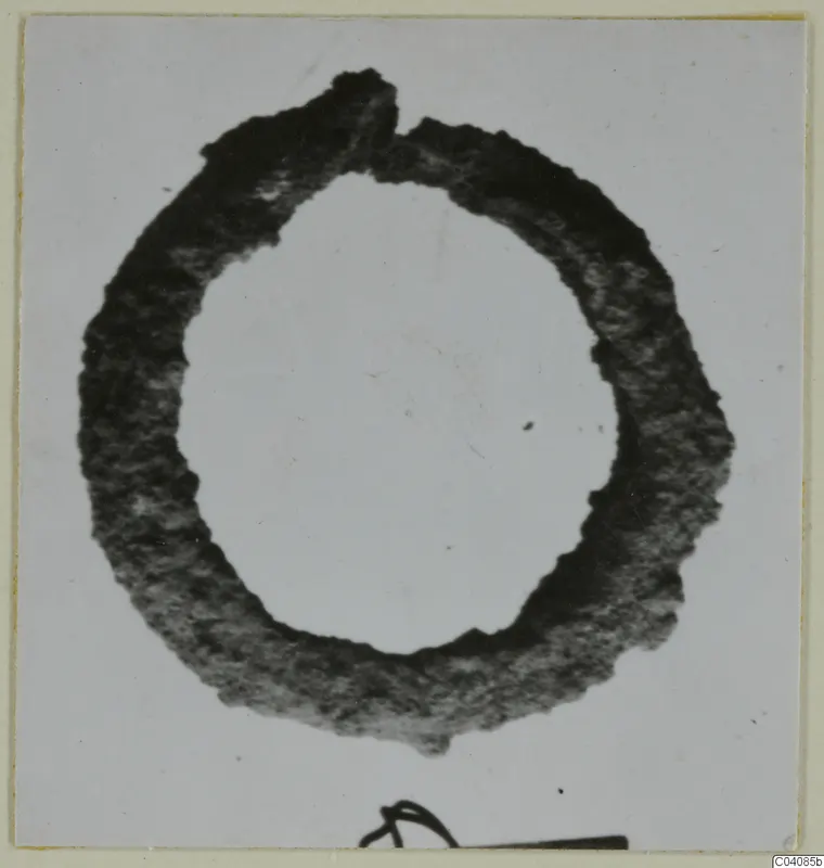 Ring-shaped silver object, dark and tarnished, shown alone against a pale grey background