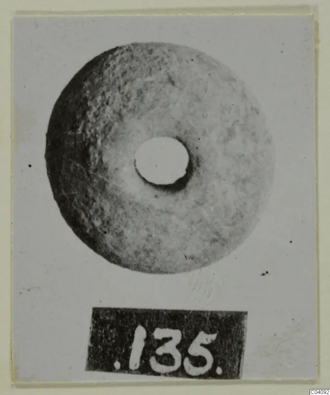 Terracotta disc with a central hole, photographed face-on with number label 135 below