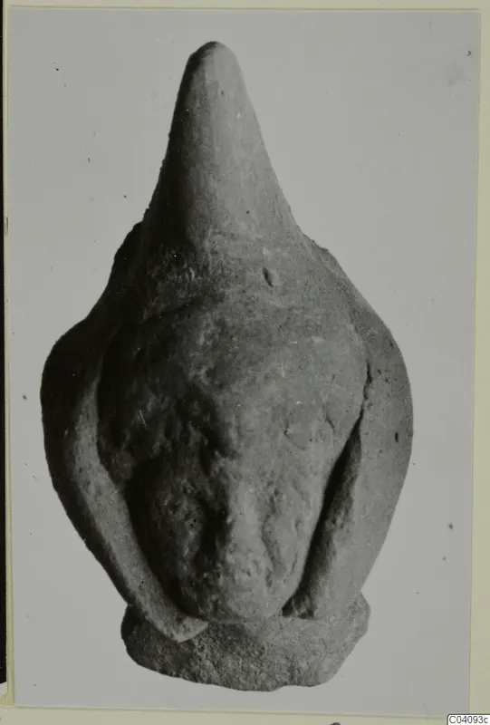 Terracotta figurine with a tall, pointed head and arms pressed against a rounded body, shown on a flat base