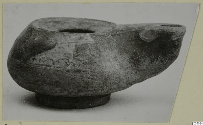 Terracotta oil lamp with a filling hole, a spout and a round base.