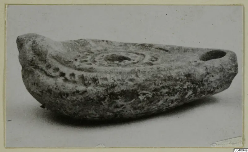 Terracotta lamp with a central ring pattern and impressed dots, photographed on a plain surface