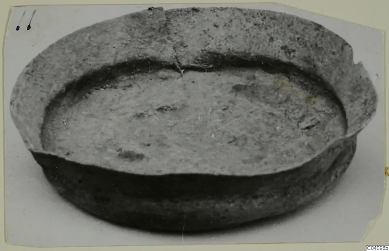 Shallow bowl with a wide, thick rim and a crack running across the rim, photographed from above at an angle.