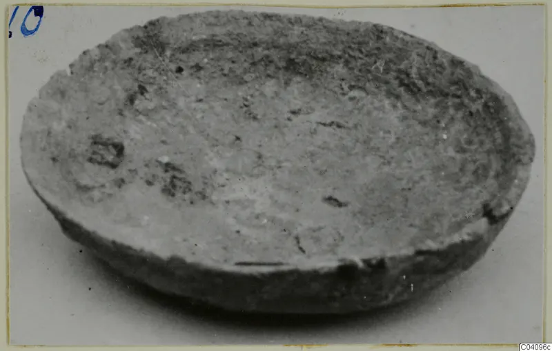 Shallow bowl with a rounded body and uneven rim, photographed at an angle on a pale background