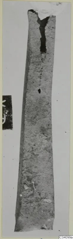 Long, tapering metal strip fragment with a split near its upper end.