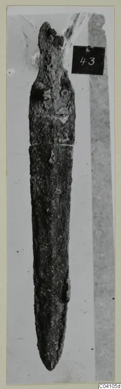 Corroded bronze blade from Ayios Iakovos Tomb 14, shown with a number label
