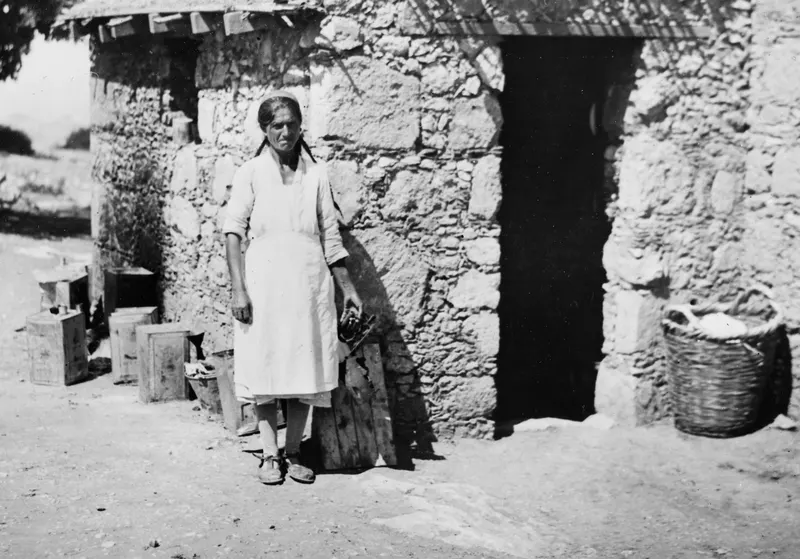 Eleni standing in front of a stone building with a dark doorway at Vouni