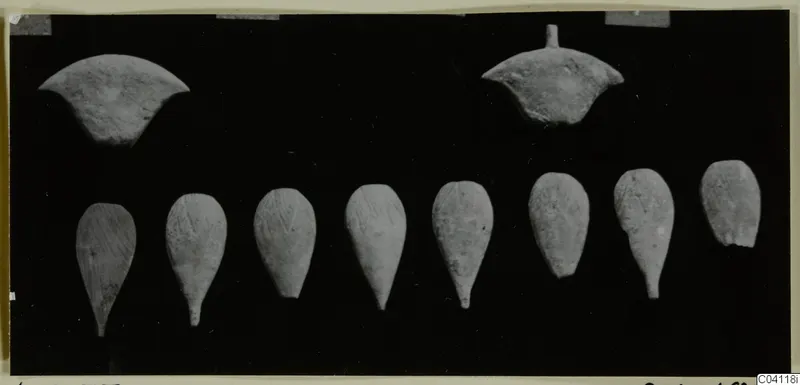Bone objects from Amathus: two curved pieces above and eight teardrop-shaped pieces in a row below, on black.