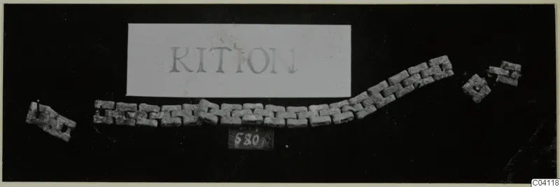 Corroded metal chain of rectangular links with two loose fragments, photographed on a black background